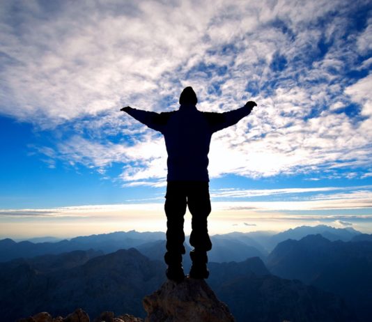 Человек раскинув руки устремляет свой взгляд на небо голубое