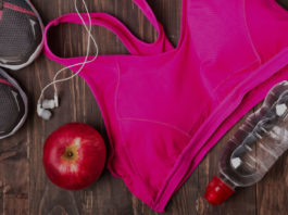 Спортивный топ, бутылка воды, наушники белые и яблоко на деревянном фоне