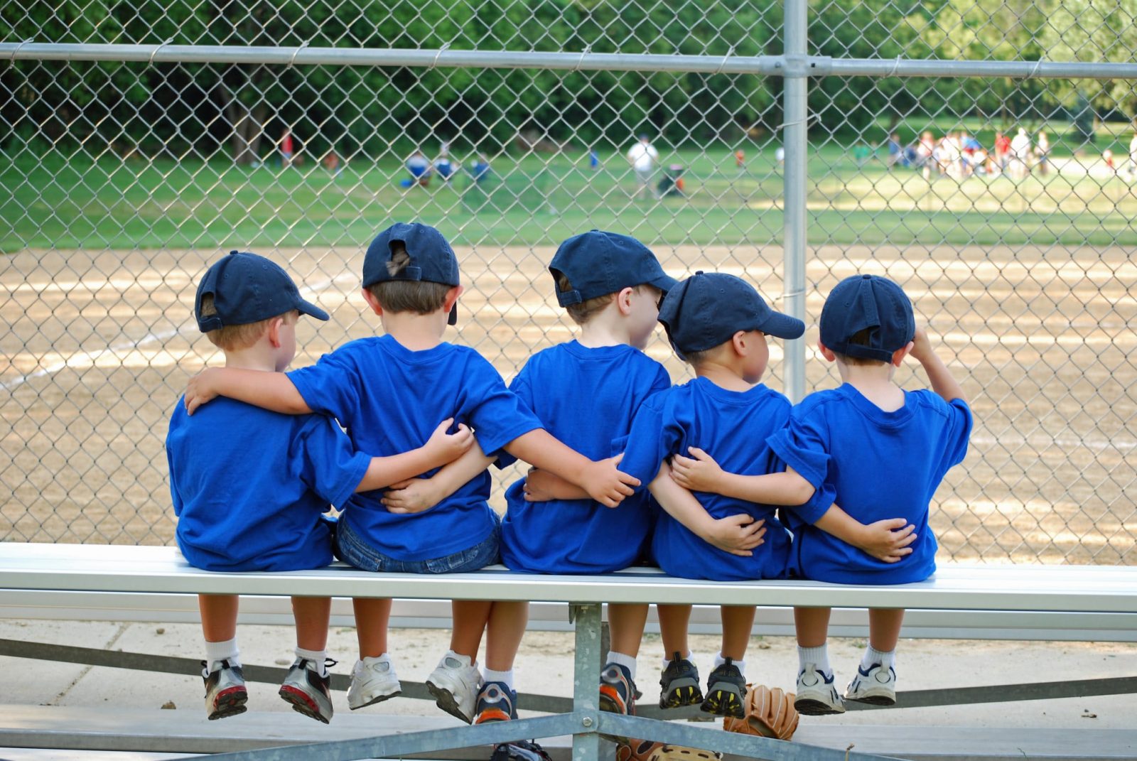 Футбольная мужская детская команда в синих футболках сидит на скамье