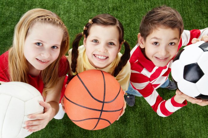 Три девочки сразными мячами спортивными: волейбольным, футбольным и баскетбольным