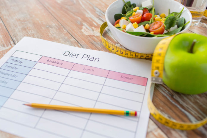 План диеты, салат, яблоко и сантиметровая лента