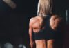 Спортивная девушка в черном топе демонстрирует мышцы спины