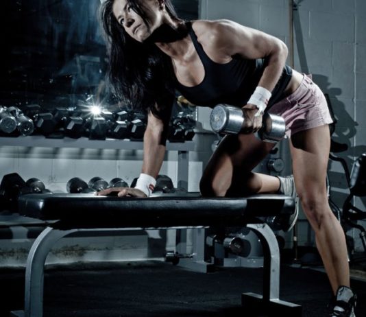 Спортивная девушка выполняет тягу гантелей в наклоне (на широчайшие мышцы)