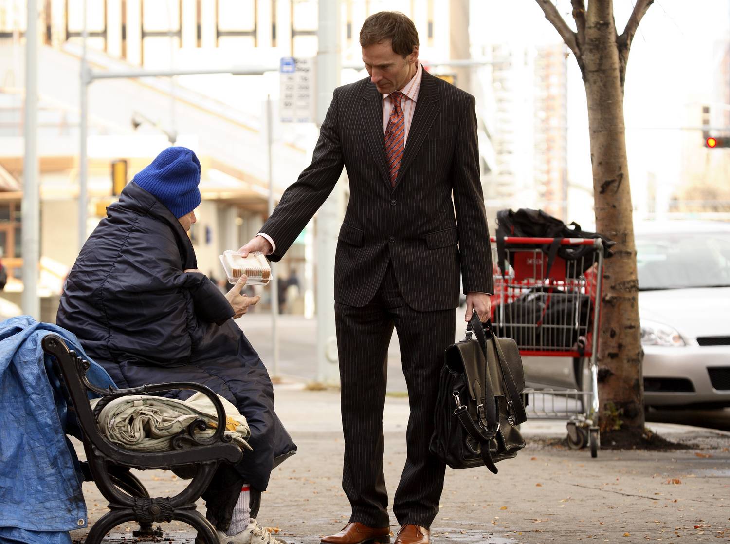 Мужчина в пиджаке делиться печеньем с бездомной старушкой