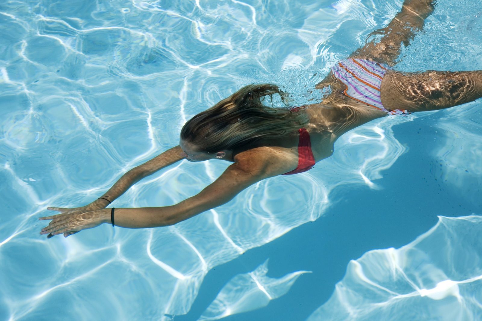 Девушка плывет под водой в раздельном купальнике