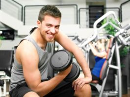 Начинающий атлет в тренажерном зале с гантелью в руке