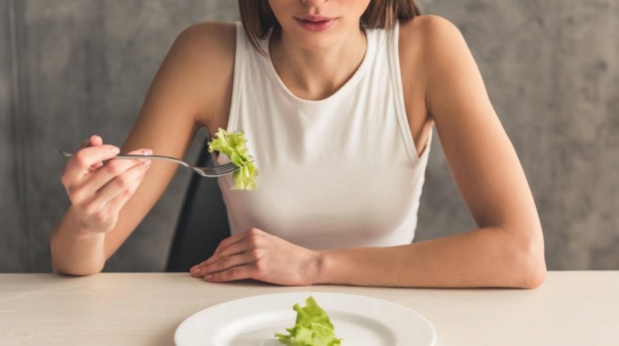 Девушка кушает салат в белой тарелке