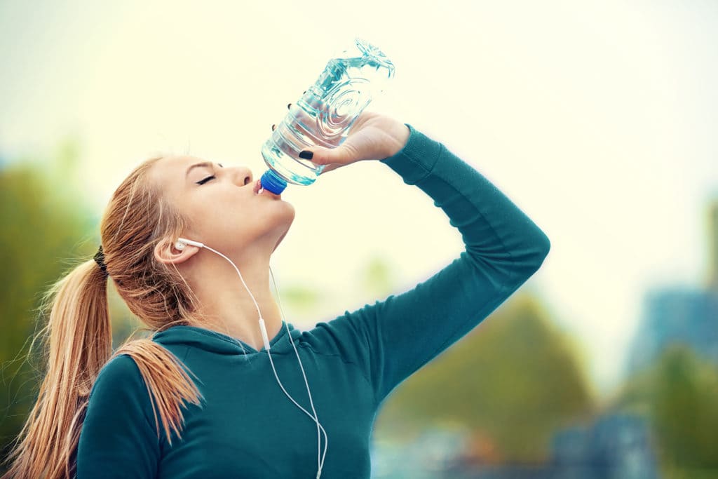Спортивная девушка пьет воду из бутылки