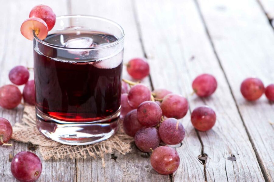 Виноградный сок в стакане на фоне грозди виноградной и текстуры