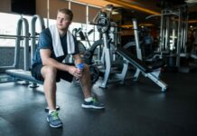 Паховая грыжа и тренировки Парень сидит на скамье в тренажерном зале